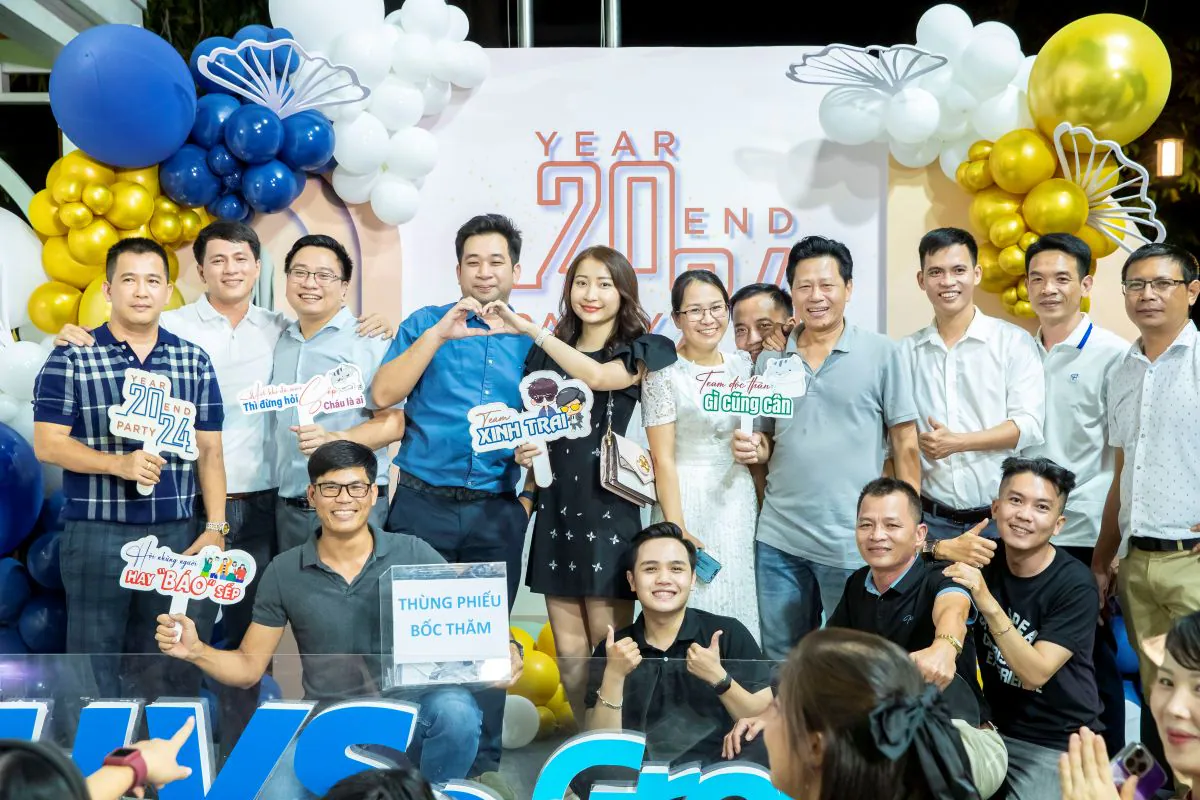 Tập thể các thành viên nam nữ của HVS Group vui vẻ tụ họp bên thùng phiếu bốc thăm may mắn trên sân khấu sự kiện tất niên.