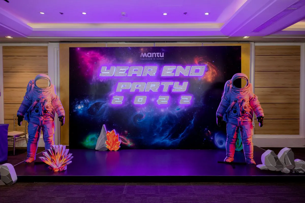 Backdrop tiệc tất niên Mantu Year End Party 2022 chủ đề A Space Odyssey với hai mô hình phi hành gia và hiệu ứng ánh sáng tím