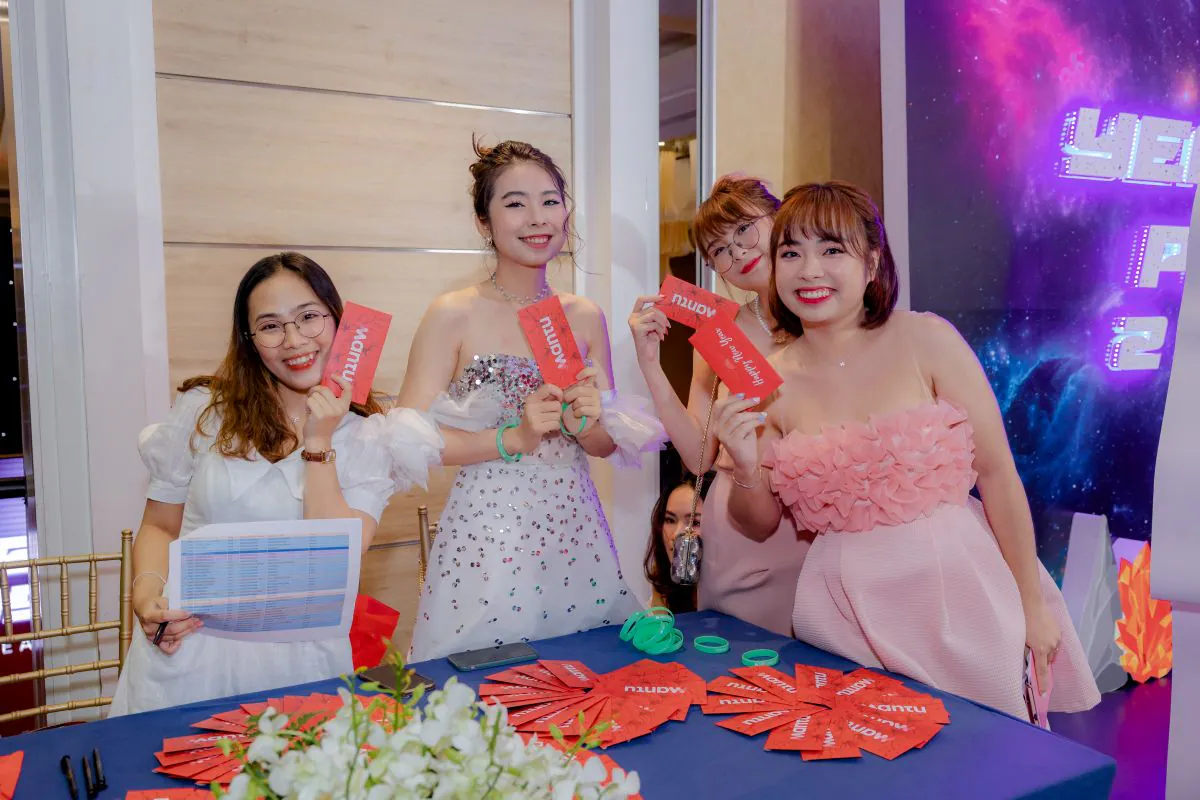 Nhóm nhân viên nữ của Mantu chụp hình kỷ niệm tại tiệc tất niên, trên tay cầm những lá thăm may mắn