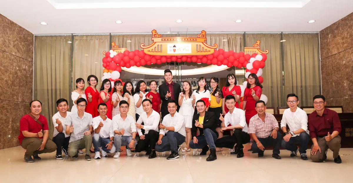 Tập thể đội ngũ Ni Hao chụp hình tập thể tại cổng chào với kiểu thả tim