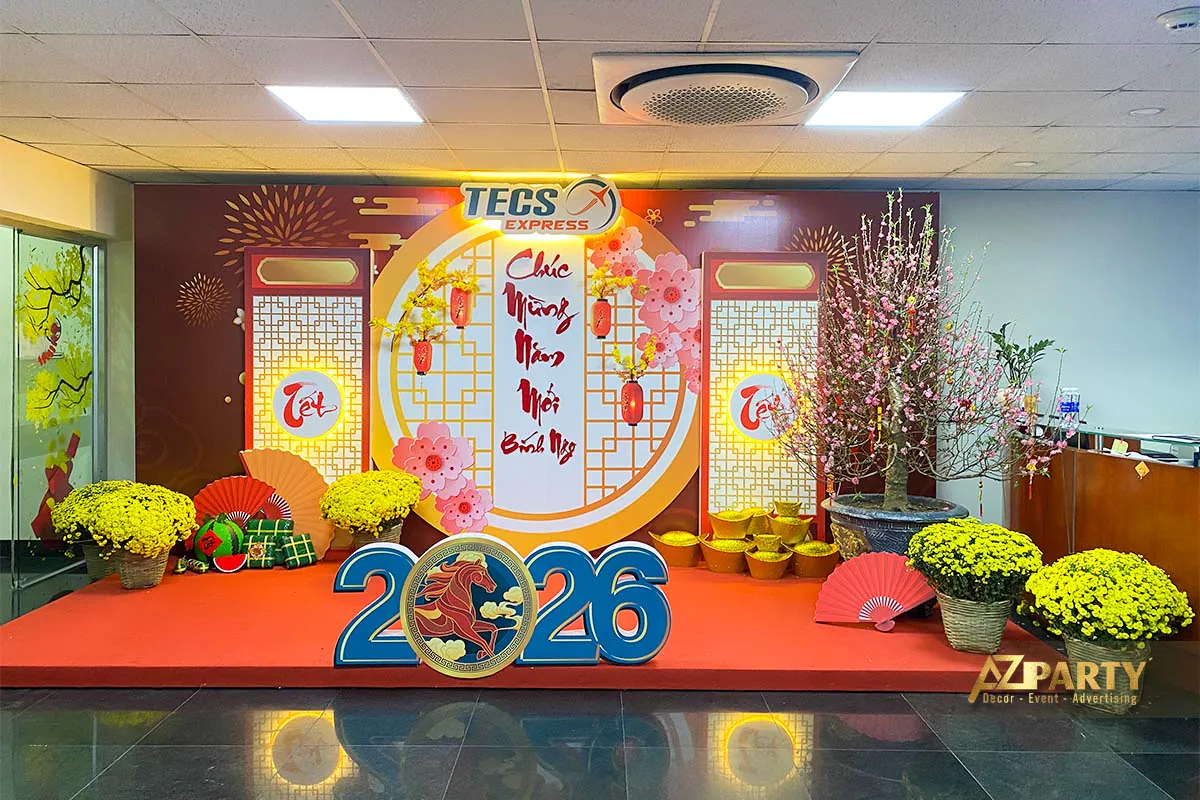 Tiểu cảnh trang trí Tết 2026 tại văn phòng TECS Express với hoa mai, hoa đào, đồng tiền vàng và backdrop Tết truyền thống