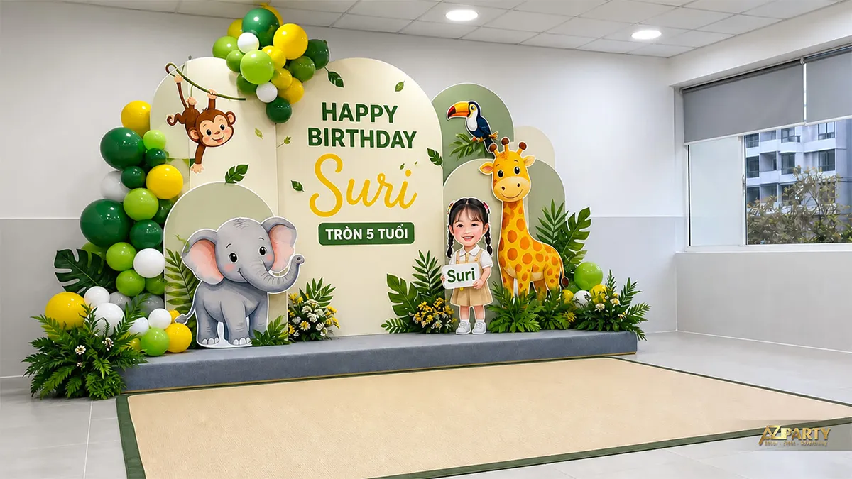 Backdrop sinh nhật tại trường cho Suri tròn 5 tuổi, chủ đề rừng xanh với khỉ, voi, hươu cao cổ và lá.
