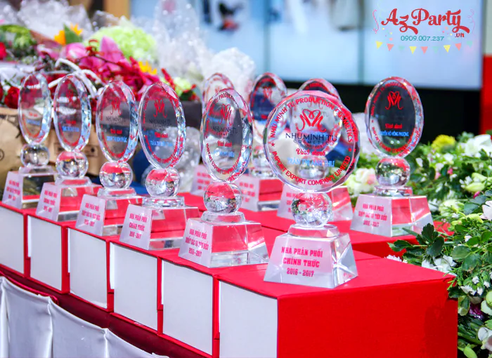 Các cúp pha lê vinh danh nhà phân phối xuất sắc của công ty mỹ phẩm Như Minh Tú xếp ngay ngắn trên bục đỏ.