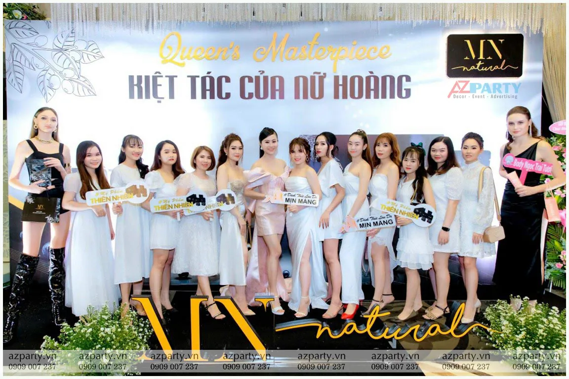 Dàn khách mời và người mẫu PG xinh đẹp chụp ảnh lưu niệm trước backdrop giới thiệu sản phẩm bột tẩy tế bào chết cafe MN Natural.