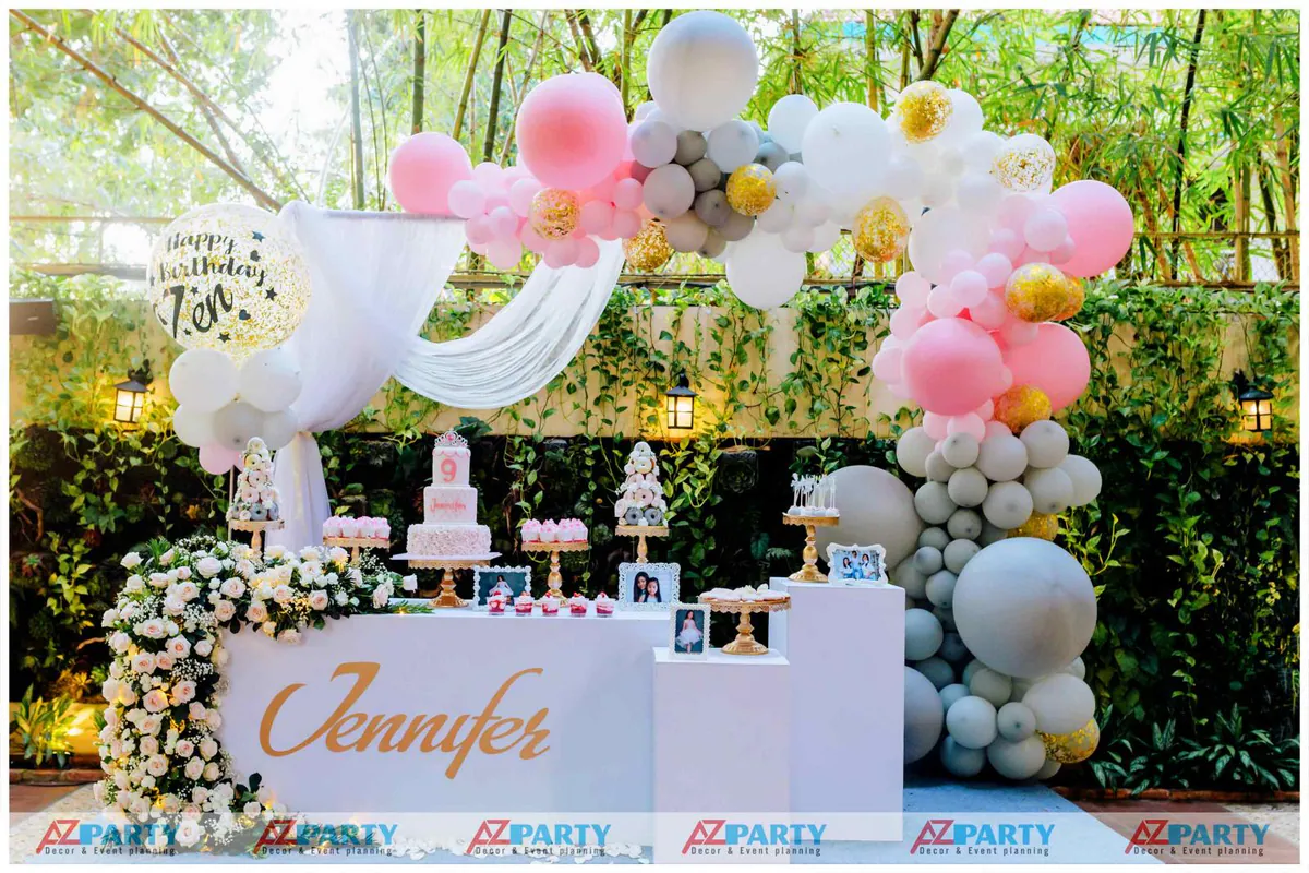 Không gian trang trí tiệc sinh nhật ngoài trời cho bé Jennifer 9 tuổi với tông màu hồng pastel chủ đạo ngọt ngào và dải bong bóng nghệ thuật bay bổng.