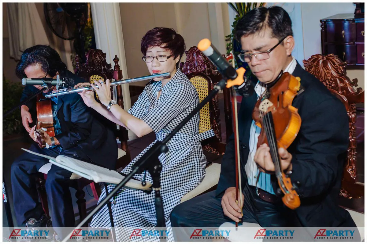 Ban nhạc hòa tấu gồm các nghệ sĩ chơi cello, sáo flute và violin biểu diễn những bản nhạc du dương phục vụ khách dự tiệc sinh nhật.