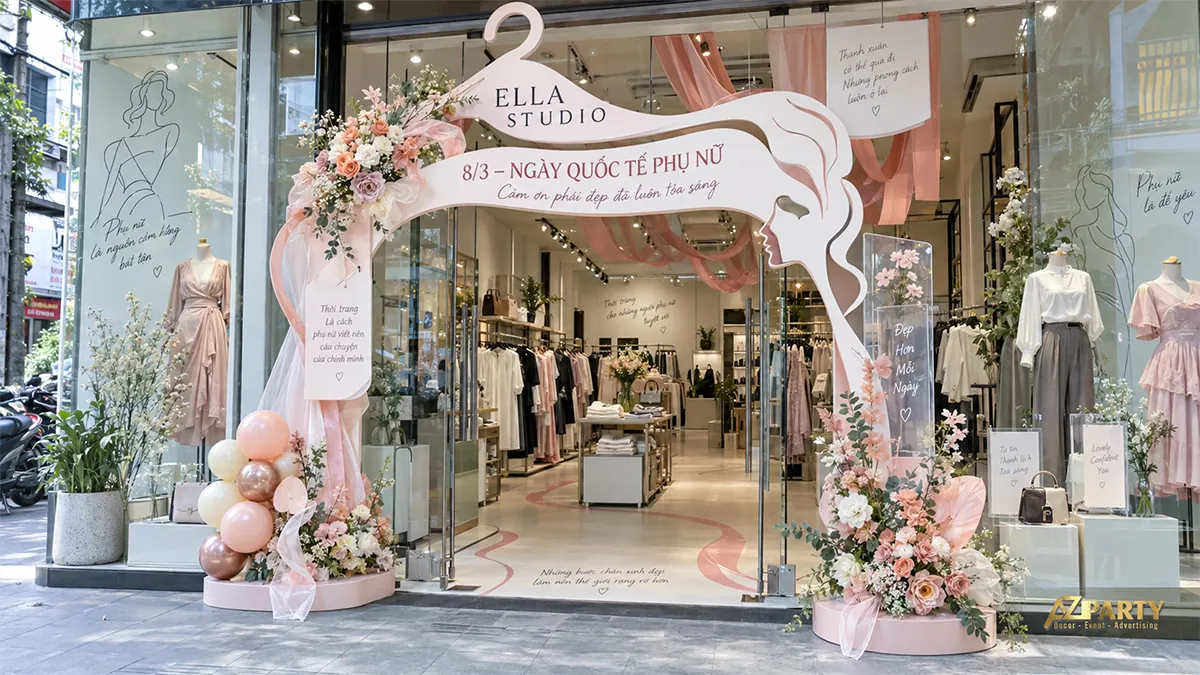 Cổng hồng kem hình móc áo và chân dung phụ nữ, hoa hai bên cửa shop cùng bóng pastel ở chân cổng
