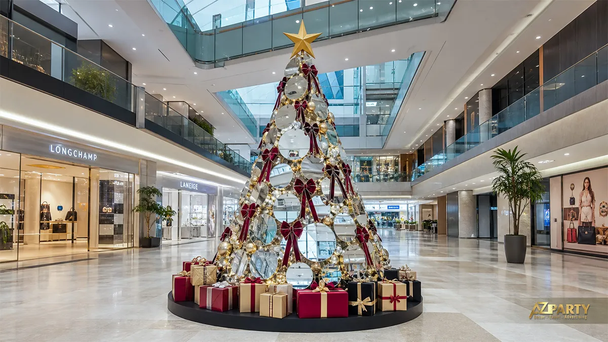 Cây thông Noel trong sảnh trung tâm thương mại với quả châu bạc, nơ burgundy và hộp quà