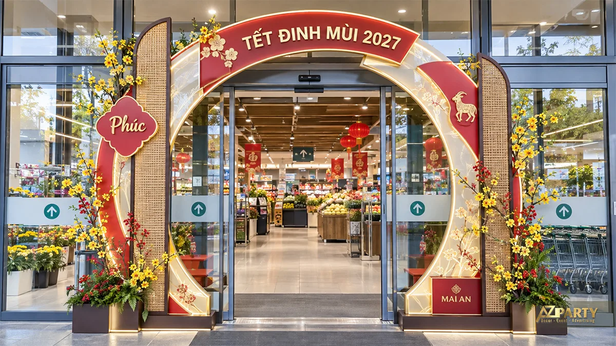Cổng vòng đỏ kem có vách mây tre, hoa và mô hình dê trước siêu thị