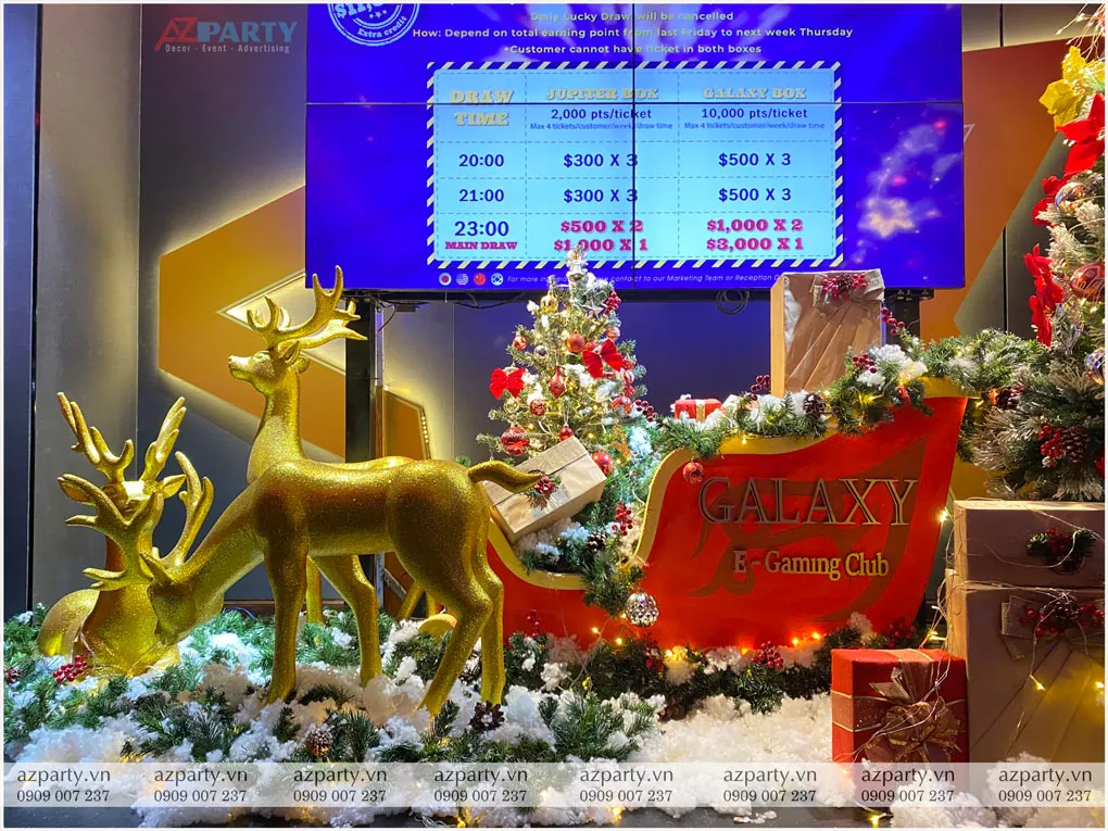 Cận cảnh khu vực trang trí Noel tại sảnh Galaxy Club với các chú tuần lộc vàng kéo xe trượt tuyết màu đỏ in logo Galaxy E-Gaming Club trên nền tuyết trắng
