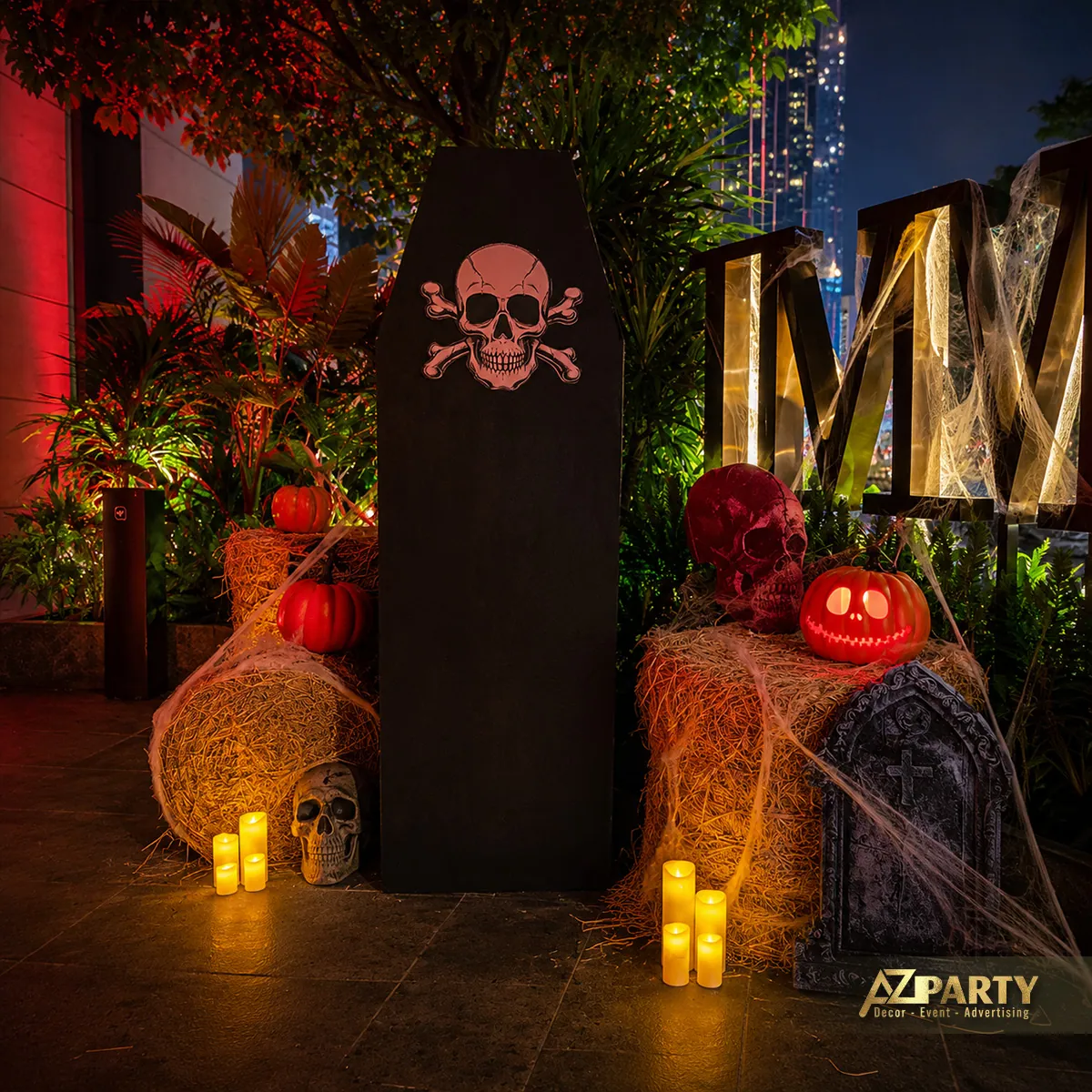 Cụm bia mộ màu đen, đầu lâu, bí ngô, bó rơm và nến được bố trí thành góc chụp Halloween.