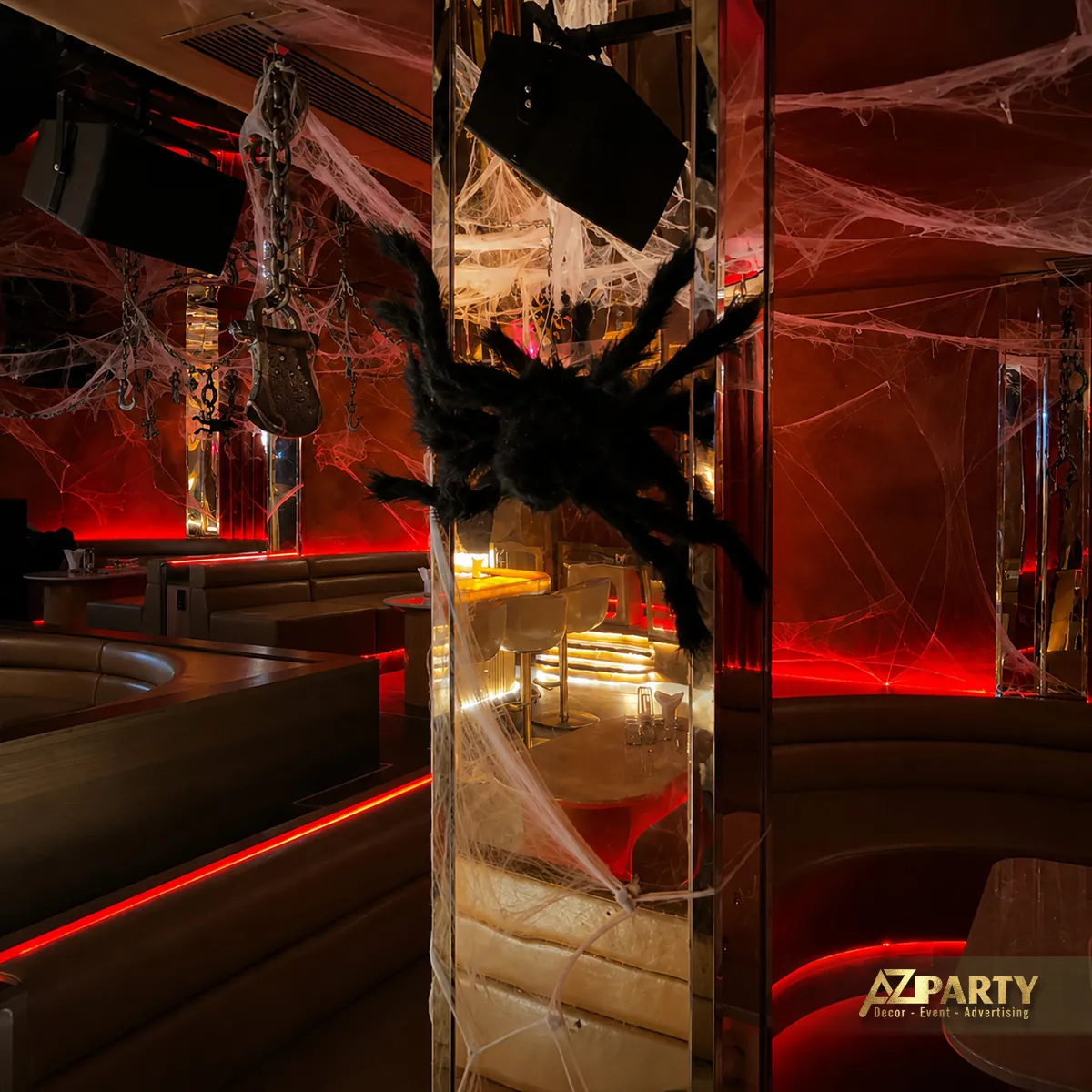 Gương lớn phản chiếu quầy bar Halloween với ánh sáng đỏ, mạng nhện và hình trang trí màu đen.
