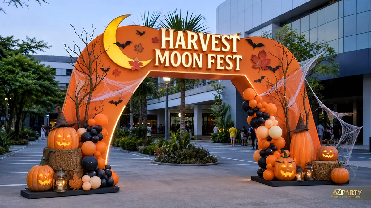 Cổng chào Harvest Moon Fest tông cam với bí ngô, kiện rơm và cụm bóng mùa thu