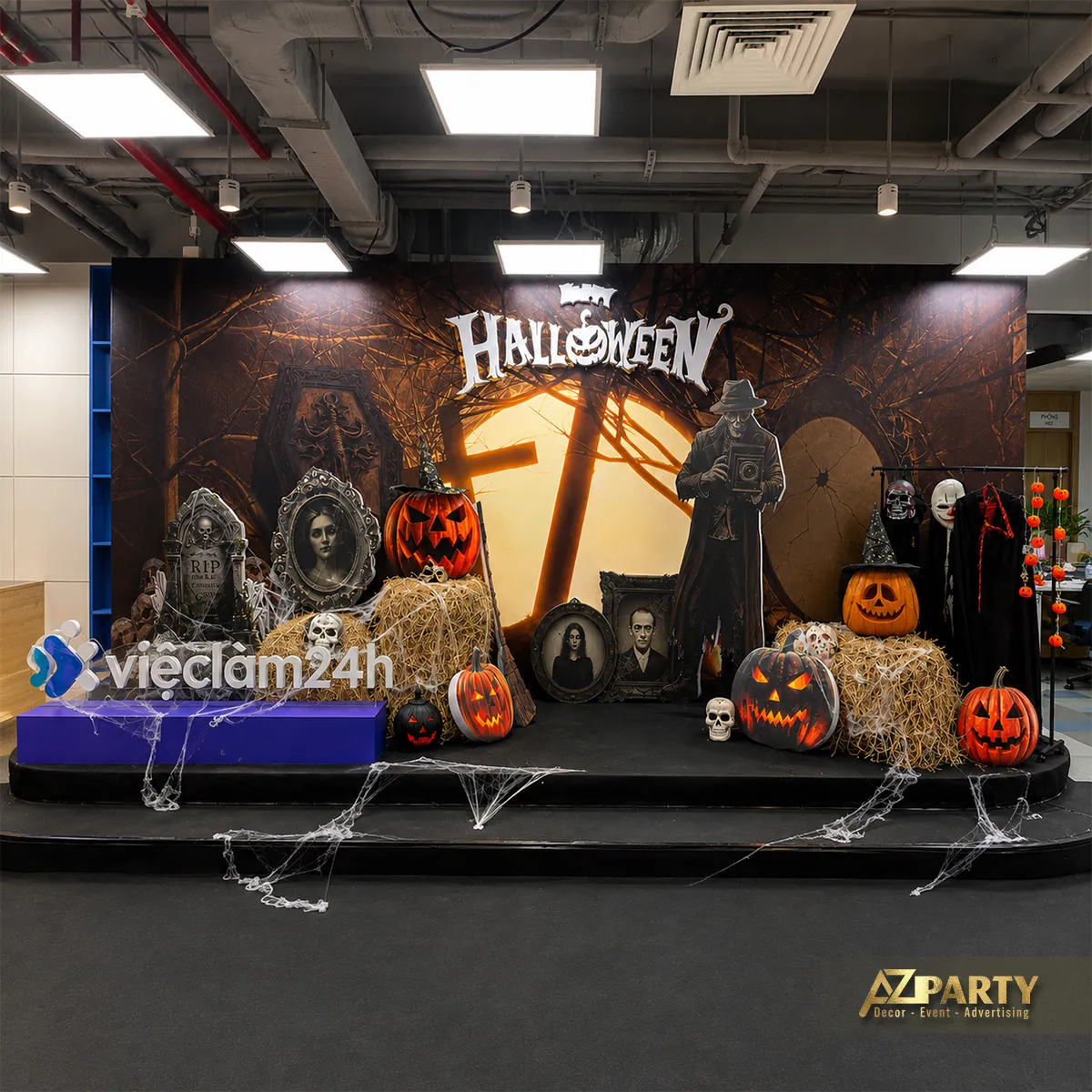 Toàn cảnh sân khấu Halloween với backdrop, logo vieclam24h, bí ngô, bó rơm và các đạo cụ ma quái.