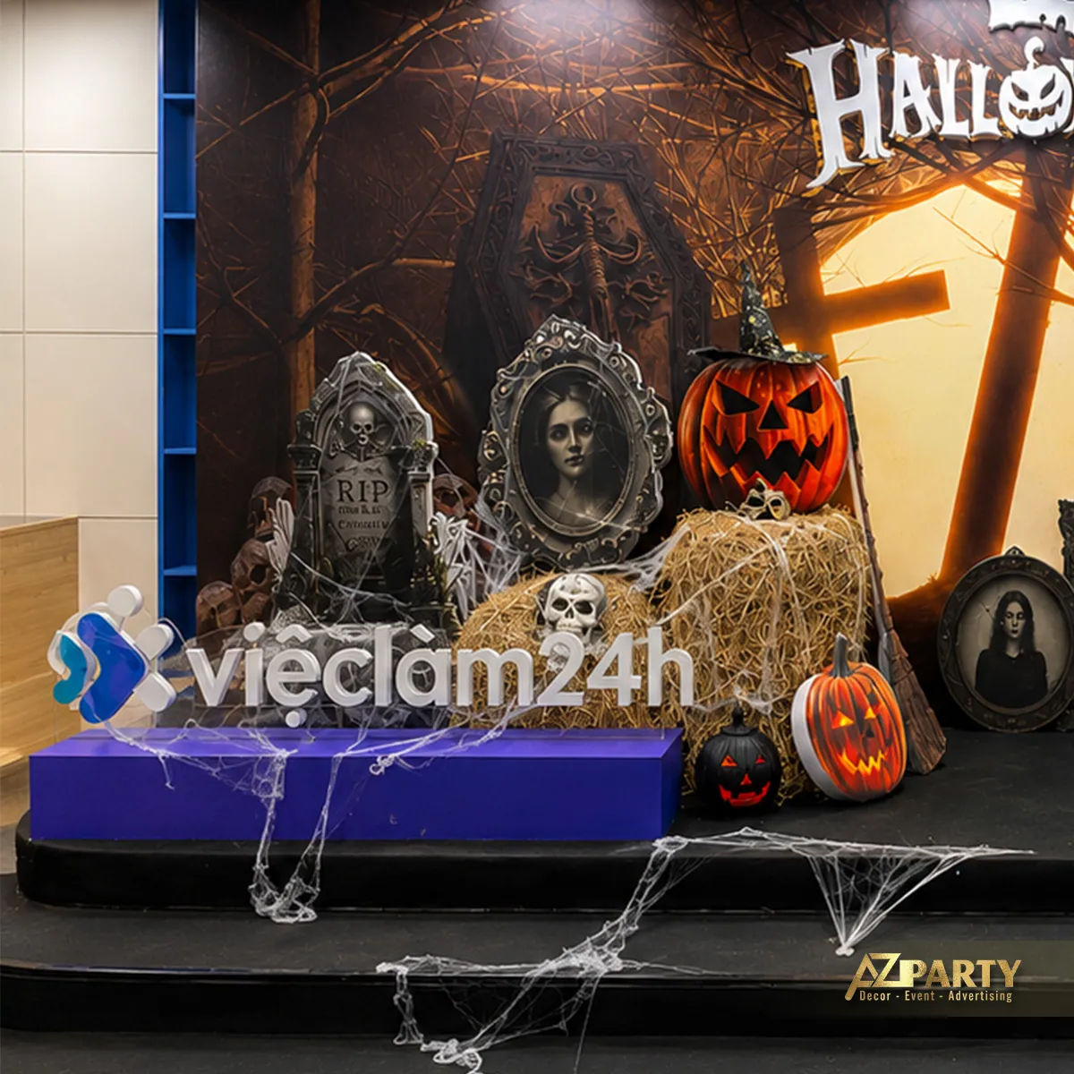 Góc phải của sân khấu với backdrop Halloween, logo vieclam24h, bí ngô và mạng nhện.