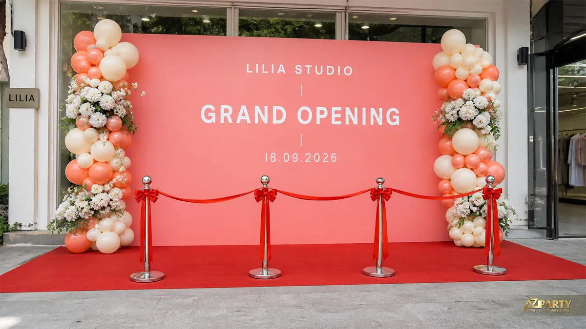 Backdrop Lilia Studio màu cam hồng với hai trụ bóng hoa và thảm đỏ phía trước