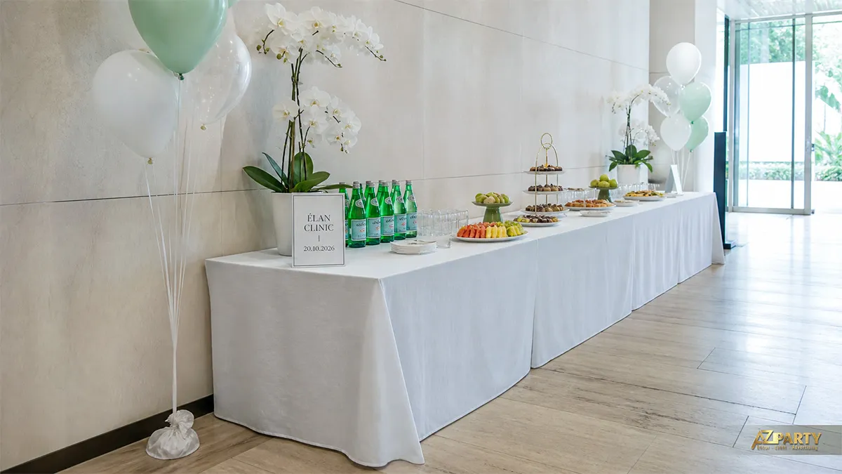 Bàn tiệc Élan Clinic với nước, bánh ngọt, lan trắng và bóng xanh mint