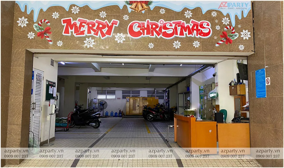 Dán decal chữ Merry Christmas màu đỏ nổi bật cùng họa tiết tuyết rơi trang trí Noel phía trên cửa vào khu vực nhà xe công ty ADC.