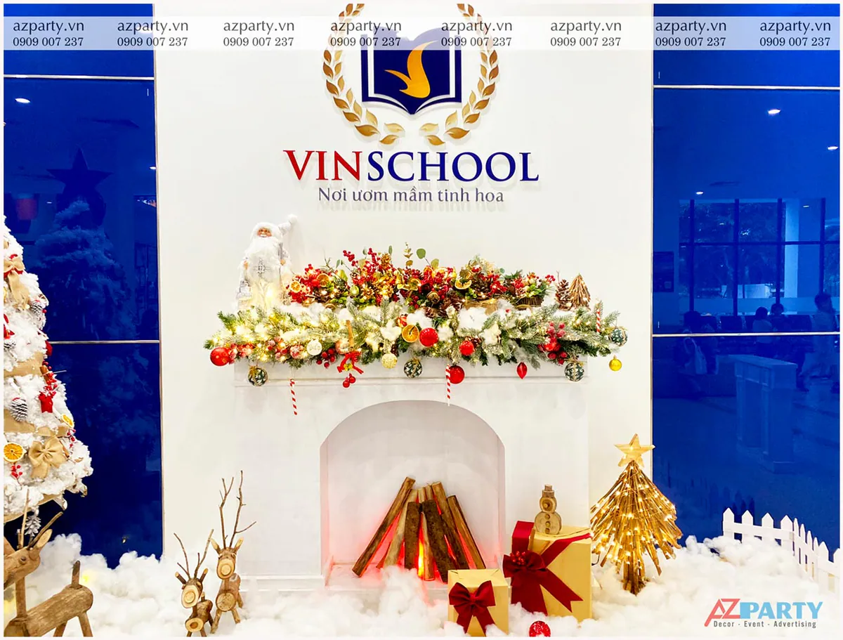 Mô hình lò sưởi giả trang trí Noel ấm áp dưới logo Vinschool kết hợp dải lá thông, quả châu đỏ rực rỡ và các hộp quà thắt nơ xinh xắn