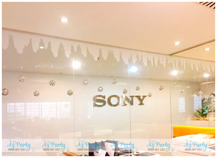Vách kính văn phòng in logo SONY được trang trí decal băng tuyết trắng rủ xuống kết hợp treo các bóng châu bạc lấp lánh nhẹ nhàng.