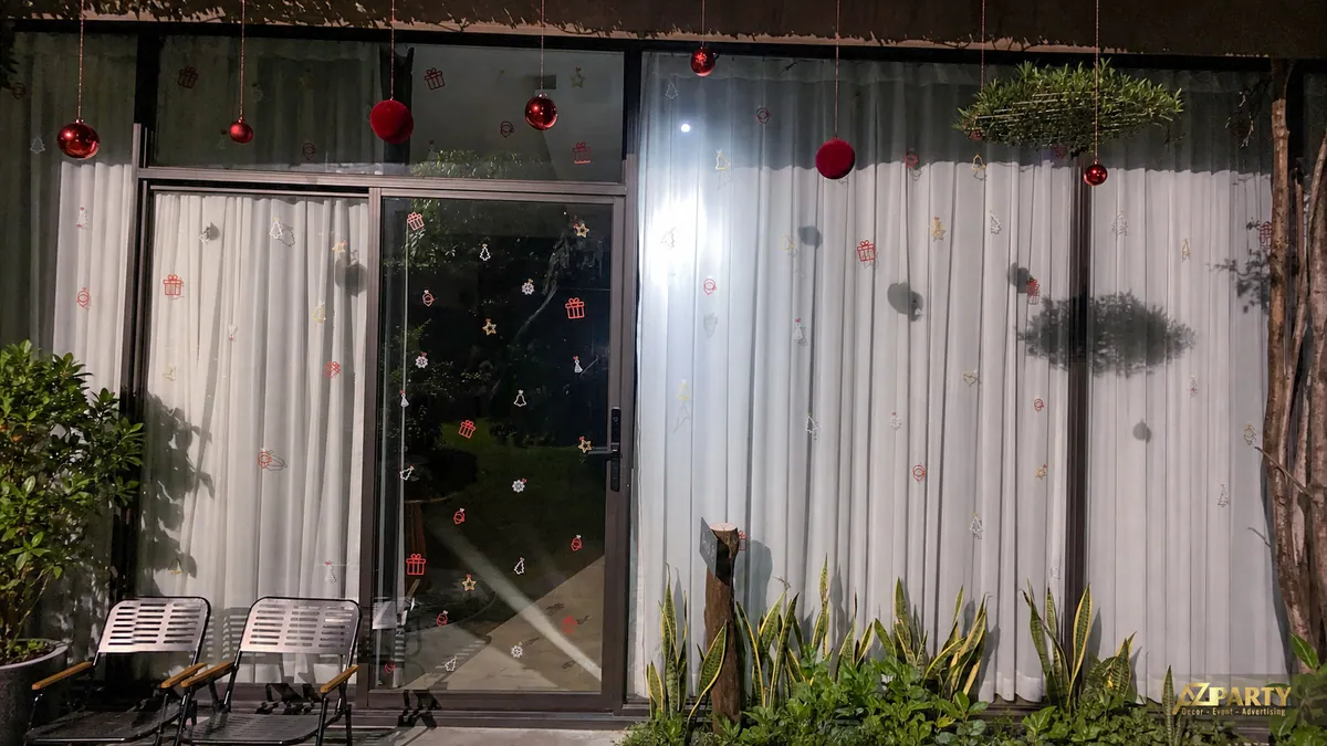 Mặt ngoài công trình với cửa kính, rèm trắng và các quả châu Noel đỏ