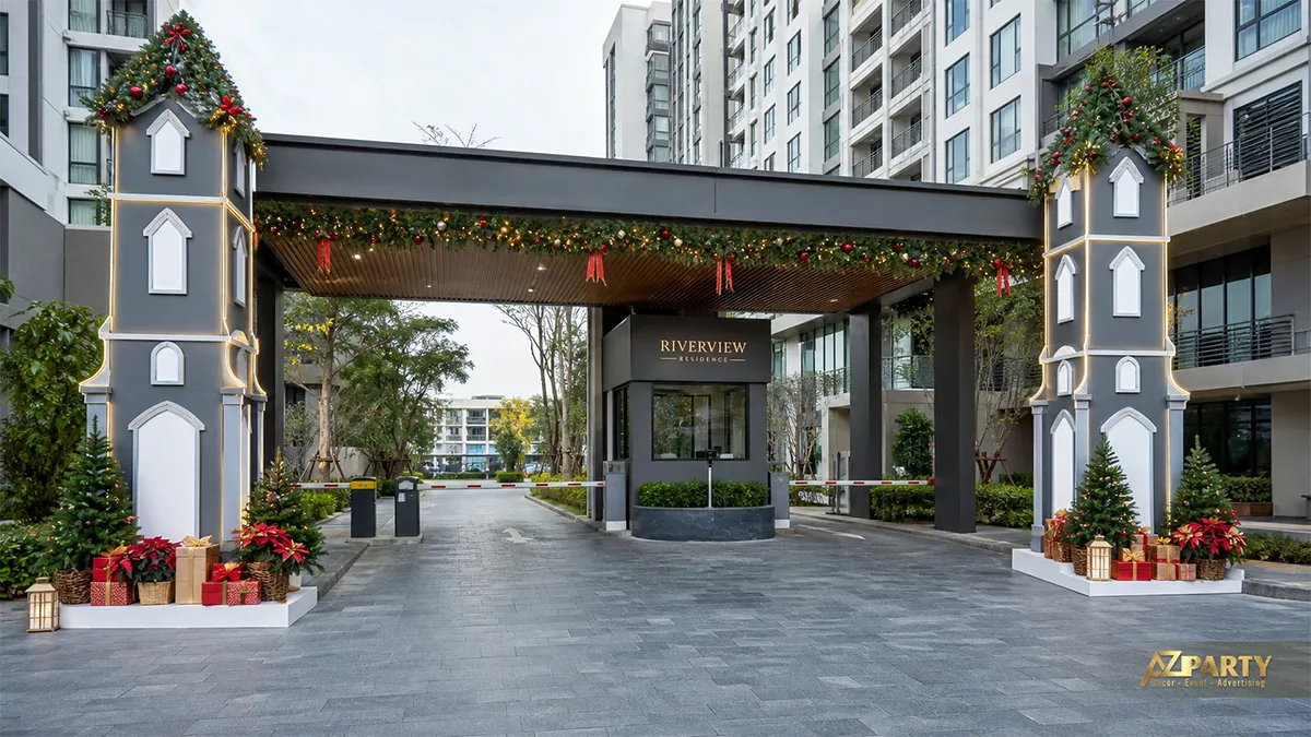 Lối xe vào Riverview Residence với trụ cổng xám, vòng lá và điểm nhấn đỏ xanh