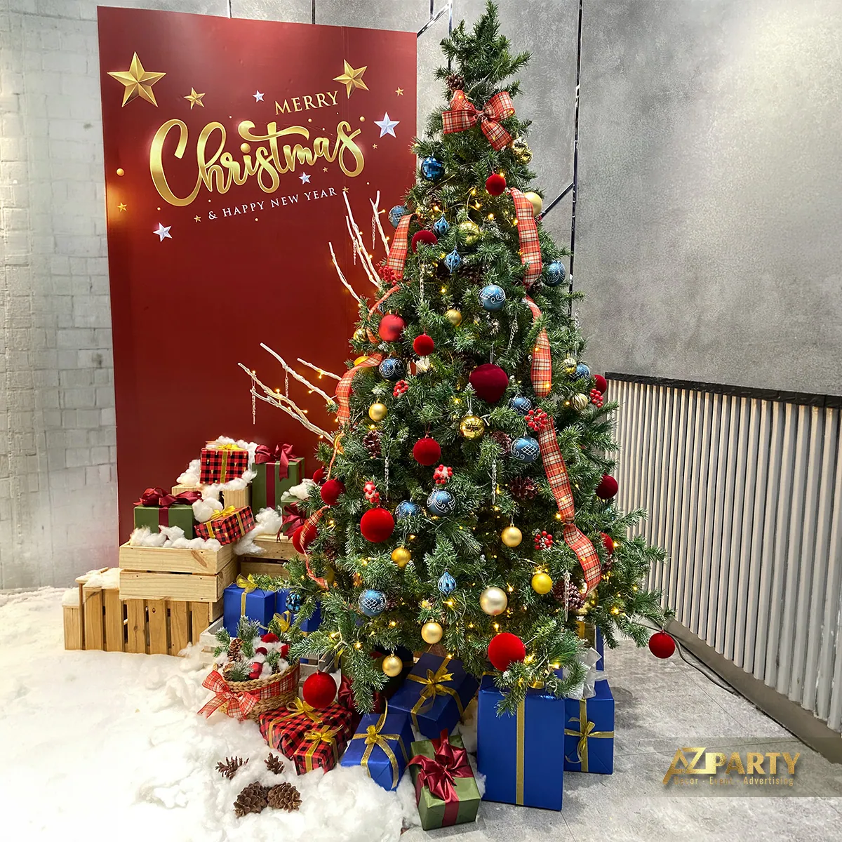 Cây thông Noel với hộp quà đặt trước phông nền đỏ có chữ Christmas