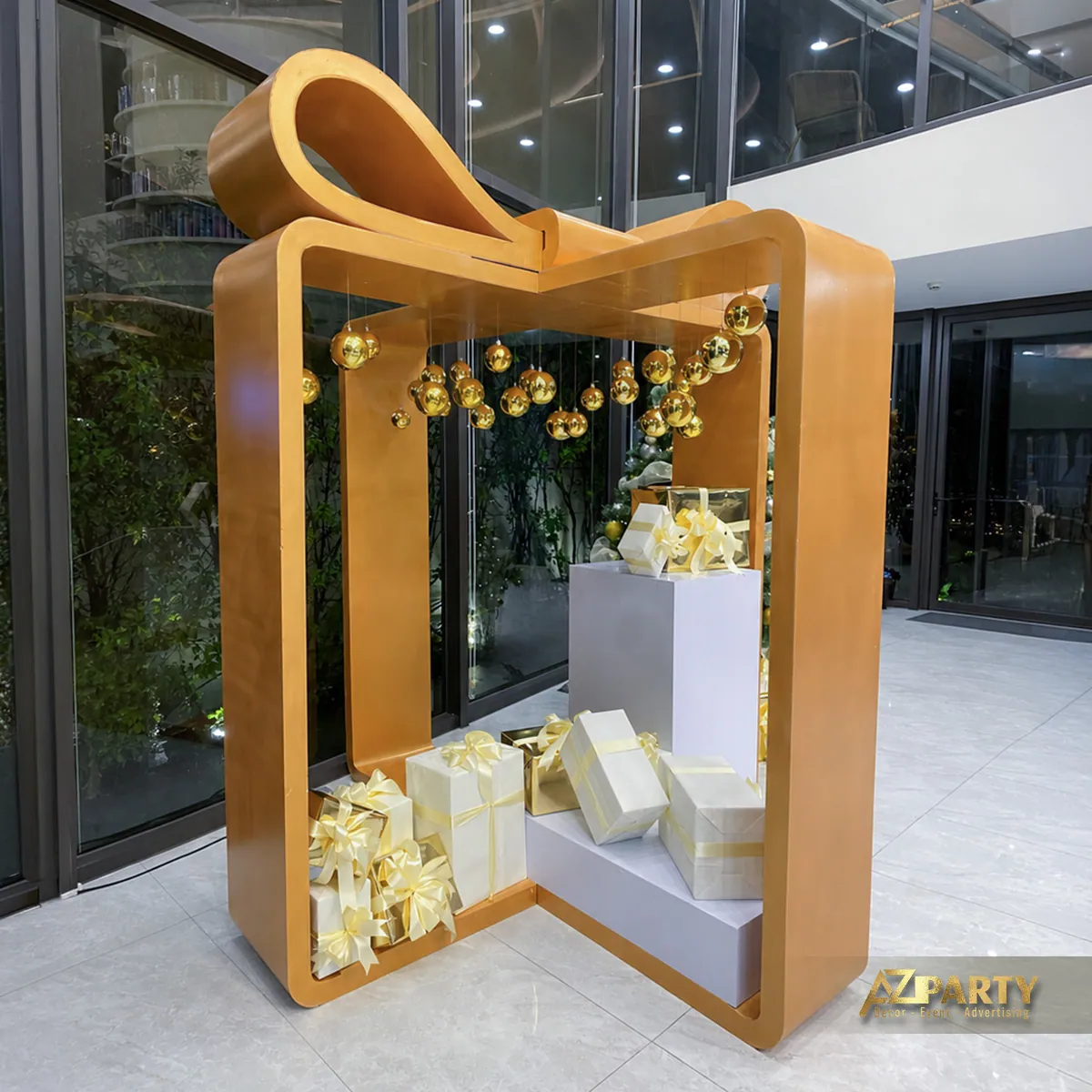 Khung hộp quà màu vàng có nơ lớn, cây thông và các hộp quà trắng