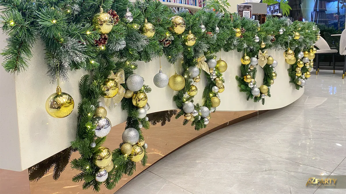 Cận cảnh dây thông Noel với quả châu vàng trắng phủ dọc quầy