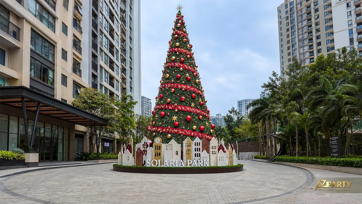 Cây thông Noel lớn trang trí quả châu đỏ trước dãy nhà mô hình tại khu đô thị