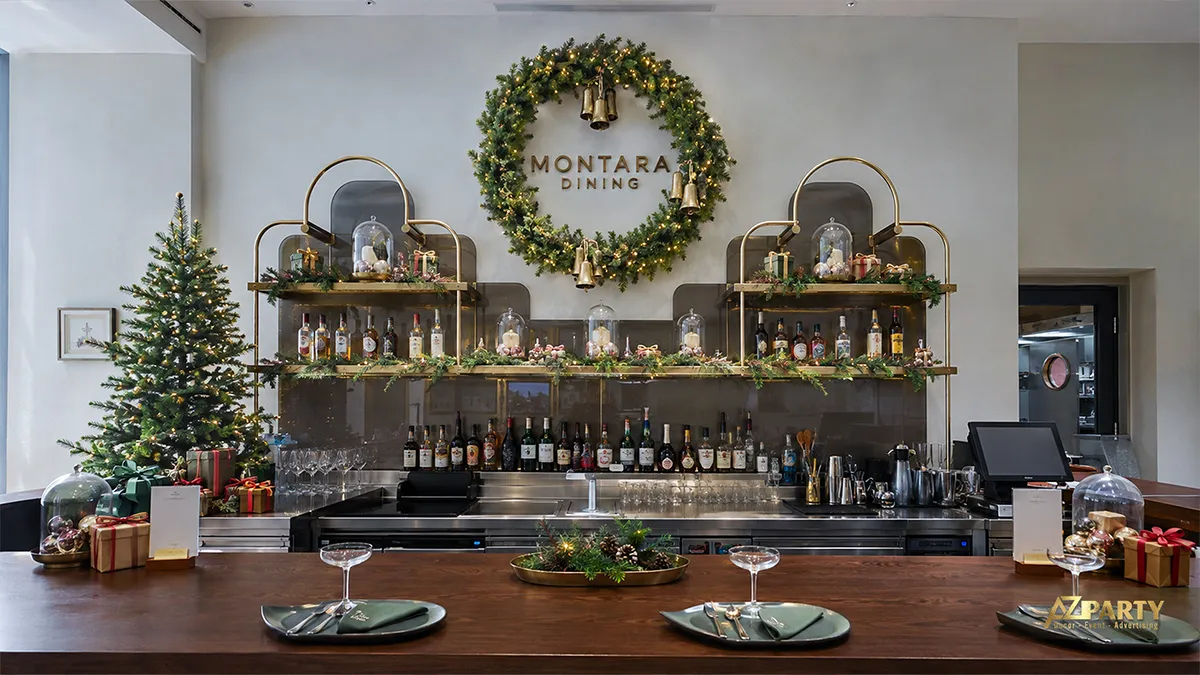 Quầy bar nhà hàng có vòng lá lớn, hai cây thông và hộp quà Noel