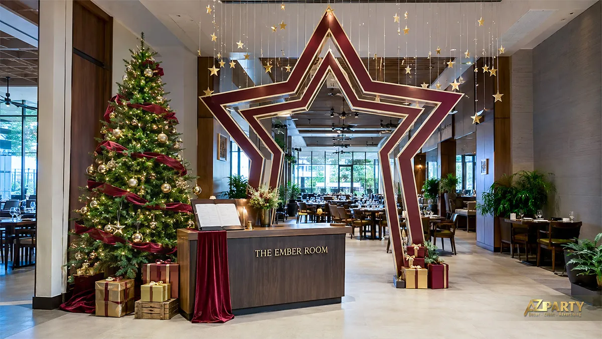 Cổng check-in hình ngôi sao đỏ vàng cạnh cây thông Noel và quầy lễ tân