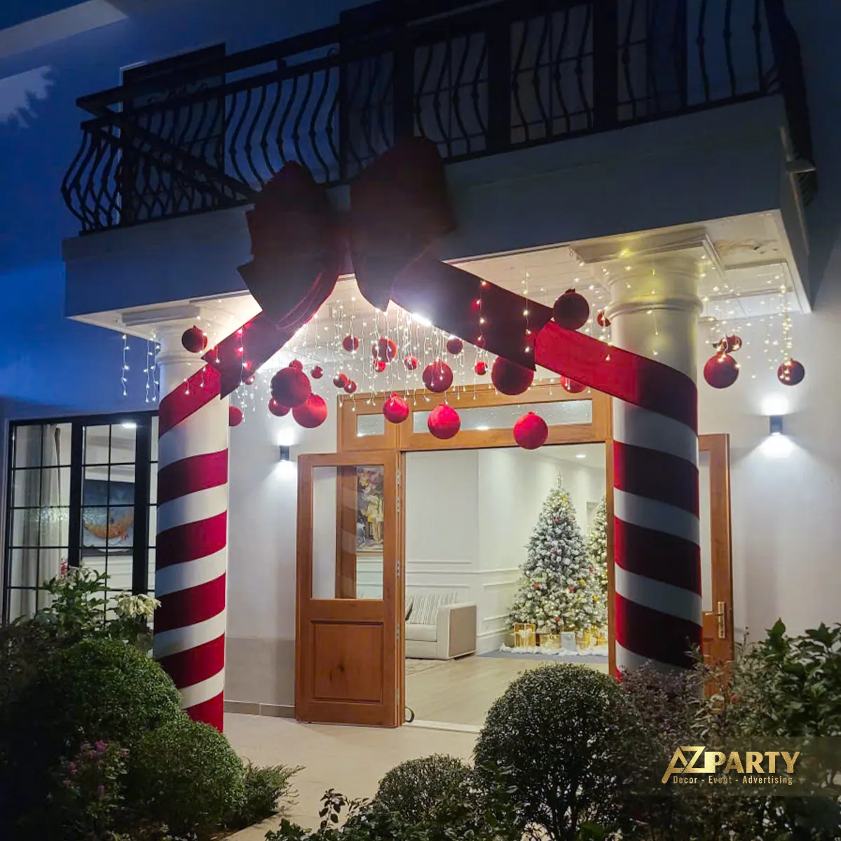 Lối vào nhà trang trí với cột kẹo sọc đỏ trắng, nơ lớn và quả châu Noel