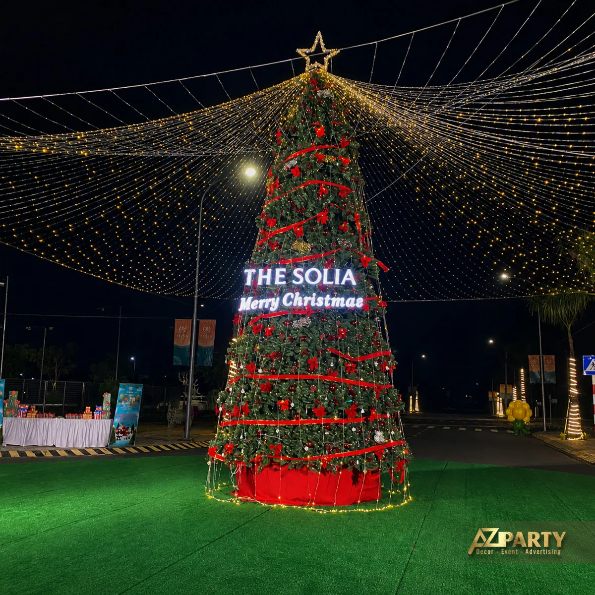 Cây thông Noel lớn thắp sáng với dòng chữ The Solia Merry Christmas trên bãi cỏ