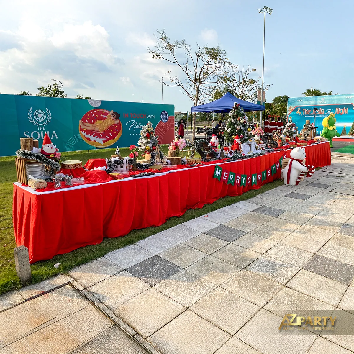 Toàn cảnh bàn trưng bày Noel phủ khăn đỏ trước backdrop ngoài trời của The Solia
