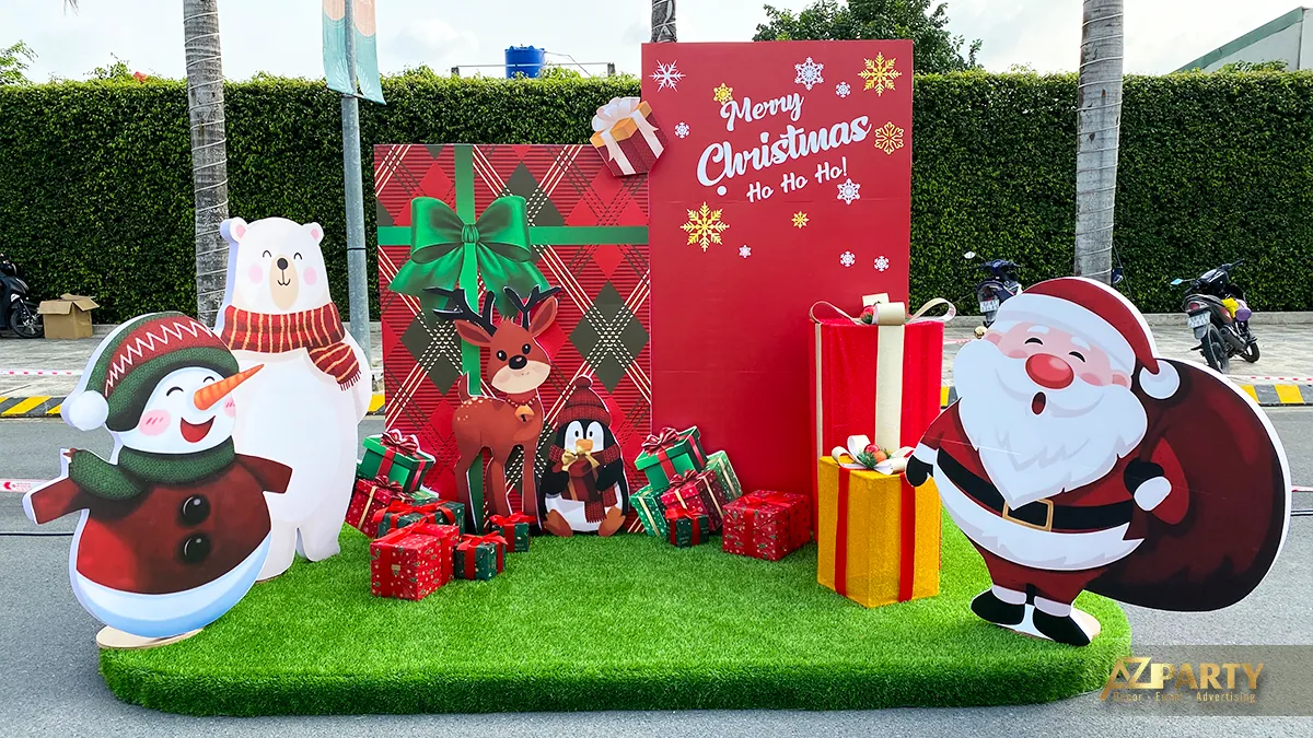 Tiểu cảnh Giáng sinh ngoài trời với ông già Noel, người tuyết, cây thông và các hộp quà trên nền xanh đỏ