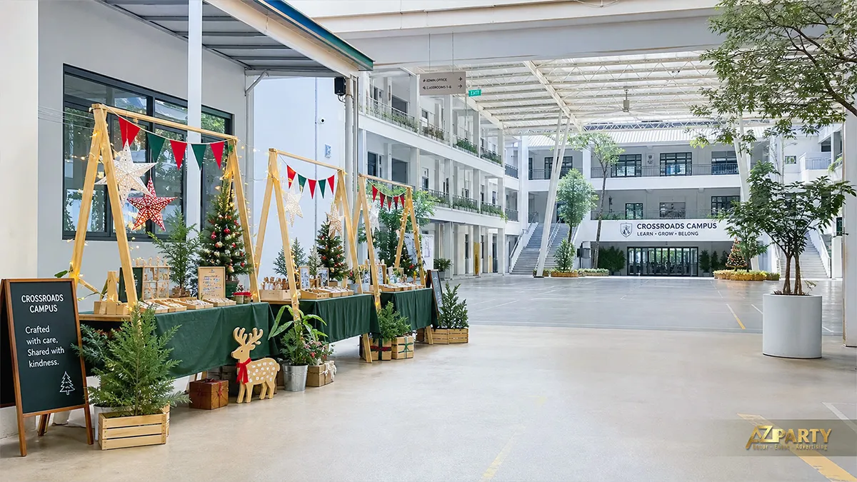 Phiên chợ Noel trong sân trường với các quầy gỗ, cờ tam giác và cây thông