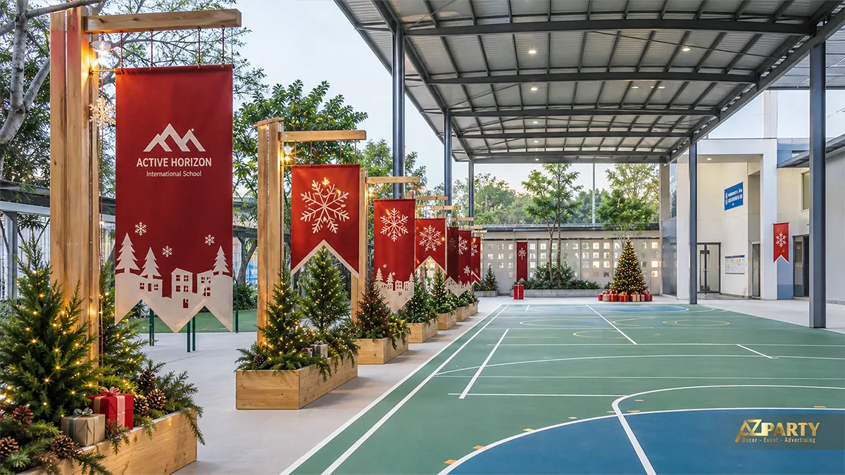 Sân thể thao có dãy banner đỏ, đèn dây và cây thông Noel