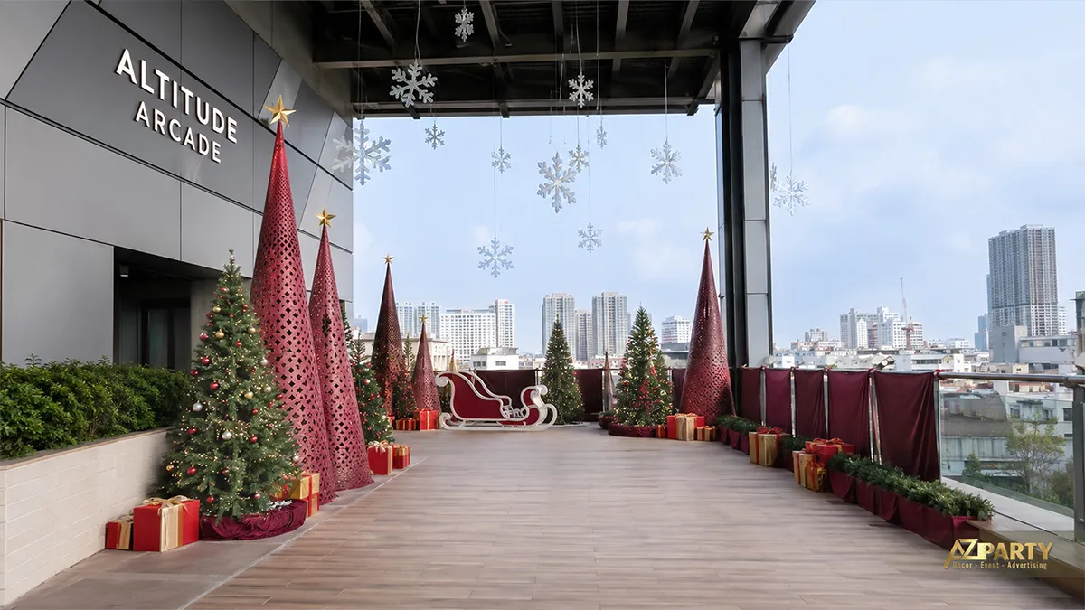 Sân thượng Noel với các cây thông đỏ, xanh, vàng tạo hình, xe trượt tuyết và thành phố phía xa
