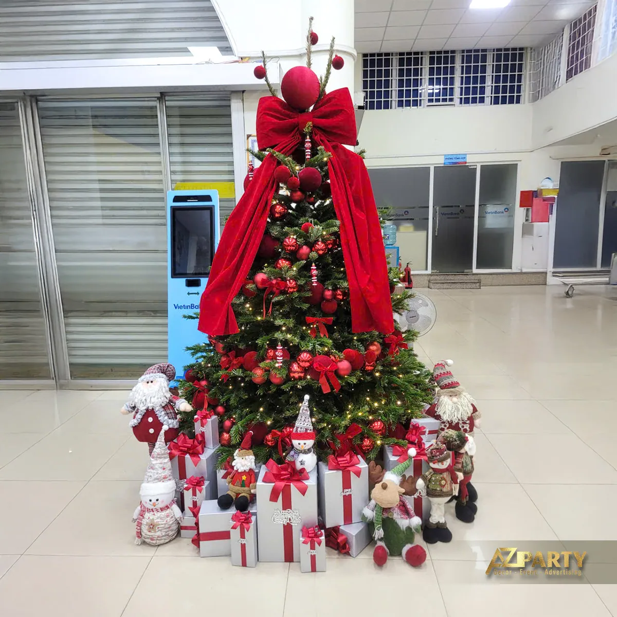 Cây thông Noel lớn với dải vải đỏ, nơ, hộp quà và đồ trang trí