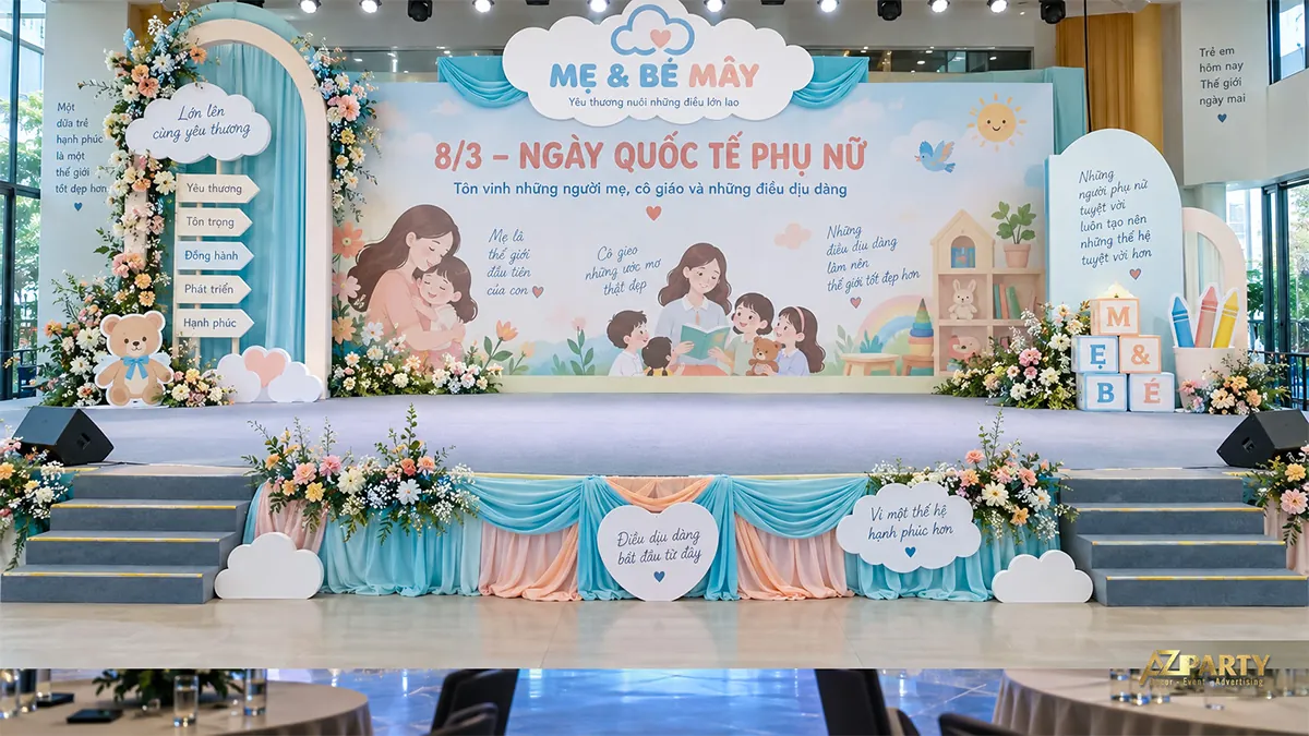 Sân khấu xanh hồng với hình mẹ con và cô giáo, mây cầu vồng, gấu bông cùng các khối đồ chơi