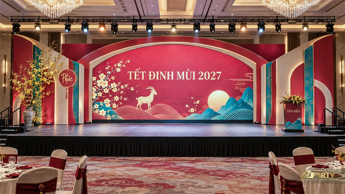 Sân khấu ballroom có khung vòm đỏ kem và tranh núi xanh dưới nắng