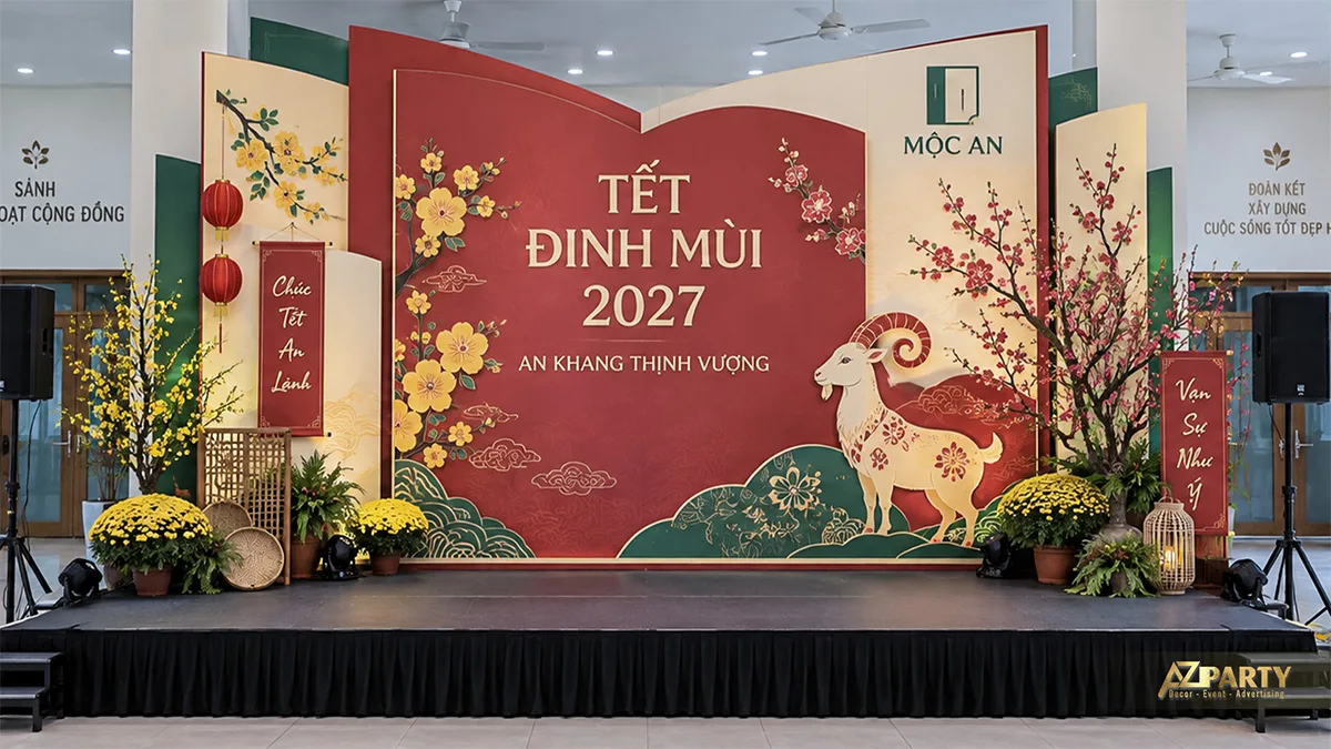 Sân khấu hội trường với phông đỏ, mảng gấp kem xanh và mô hình dê