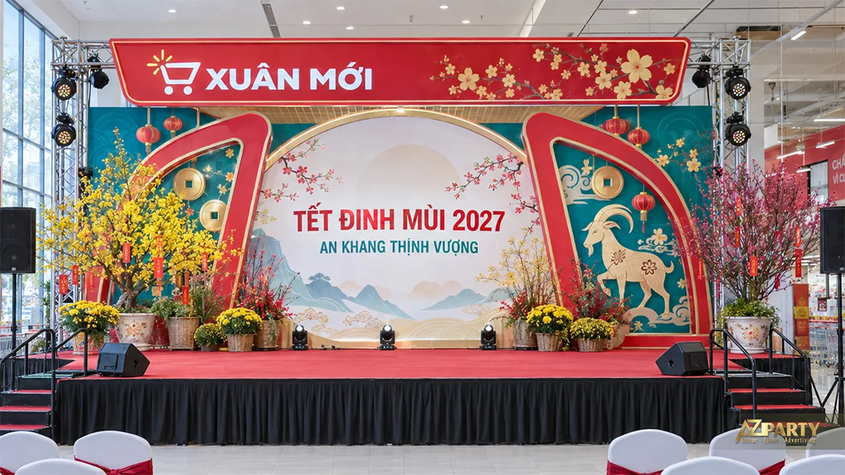 Sân khấu trung tâm thương mại với khung đỏ xanh, đèn lồng và cây mai