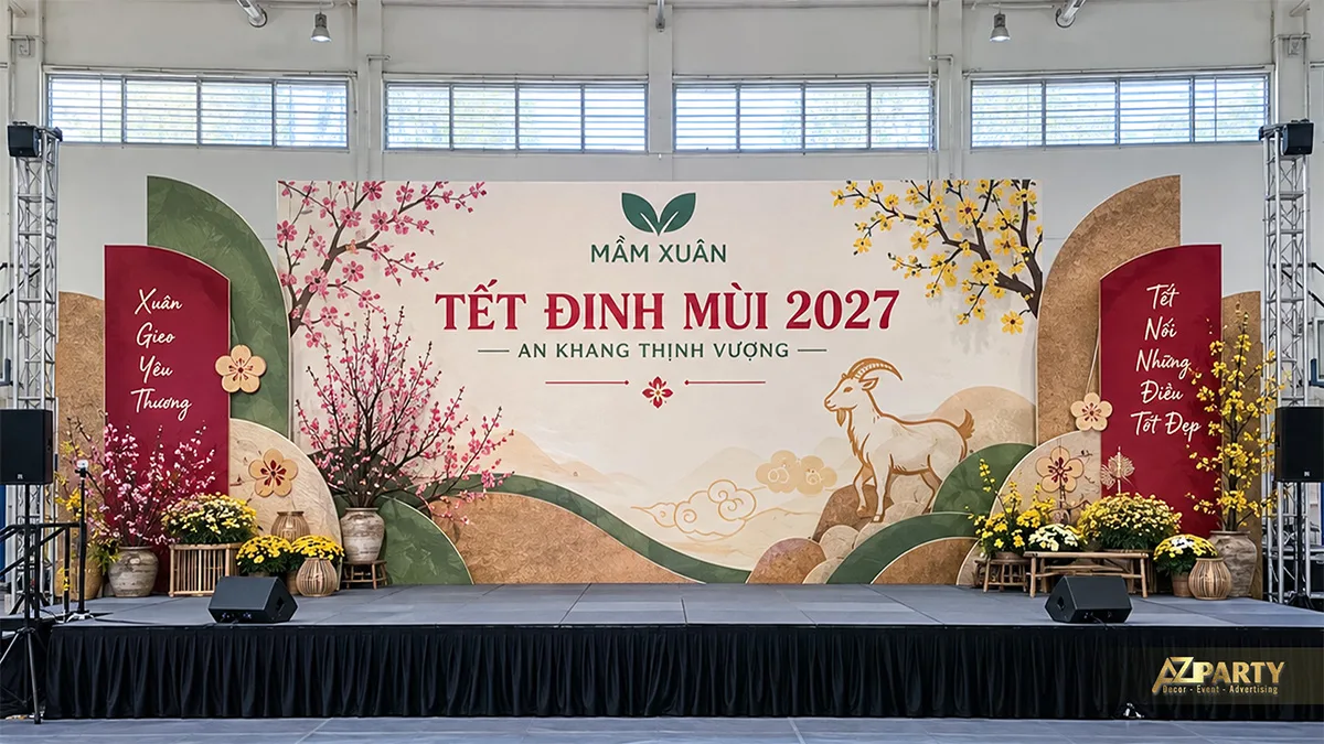 Sân khấu nền kem với mảng đồi xanh, hoa mai đào và mô hình dê