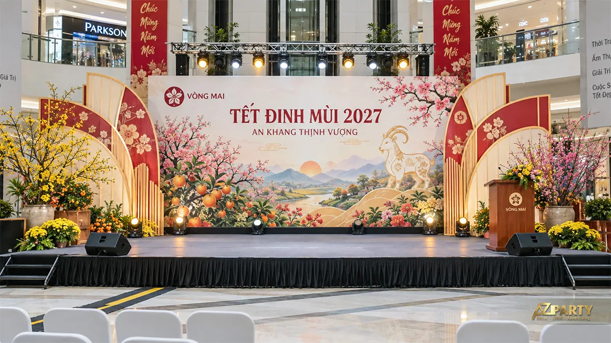 Sân khấu tại trung tâm thương mại có cây quất, mảng vòm đỏ kem và bục phát biểu