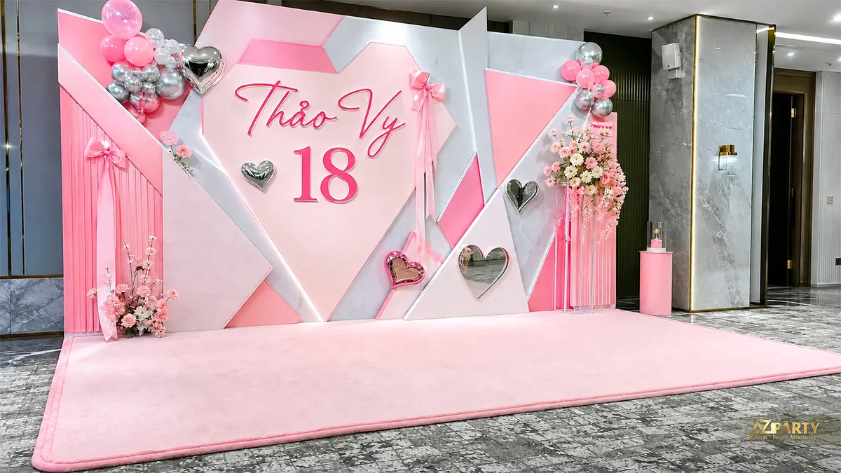 Backdrop sinh nhật 18 tuổi cho Thảo Vy tông hồng, phối hình trái tim, nơ, hoa và bóng ánh bạc.