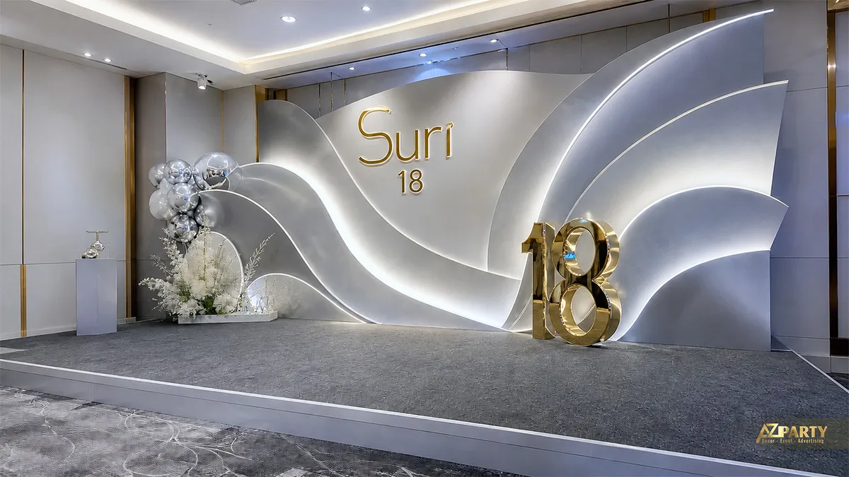 Backdrop sinh nhật 18 tuổi cho Suri tông bạc trắng, phối đường nét uốn lượn và số 18 gold.