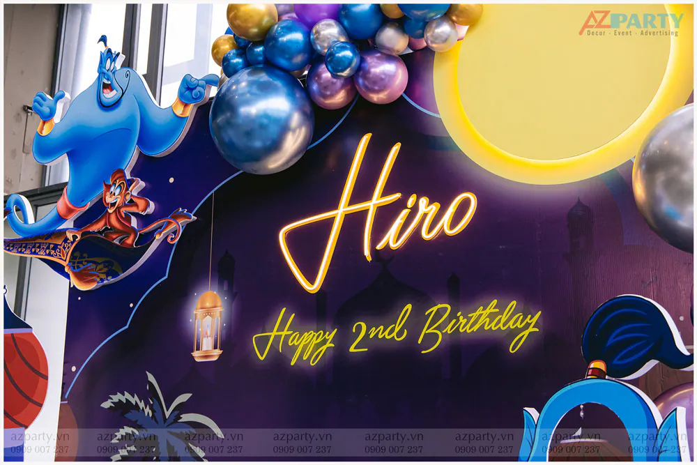 Bảng chữ đèn LED neon phát sáng màu vàng ấm 'Hiro Happy 2nd Birthday' được thiết kế tinh tế trên nền backdrop đêm hoàng cung.