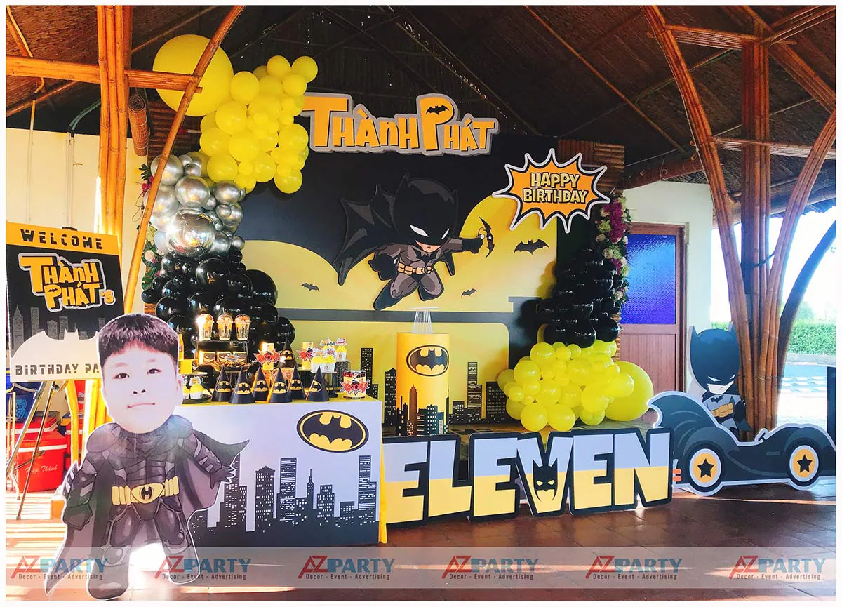 Trang trí tiệc sinh nhật bé trai Thành Phát chủ đề The Batman với backdrop hình thành phố Gotham, bóng bay tông đen vàng huyền bí và mô hình Batmobile ấn tượng.
